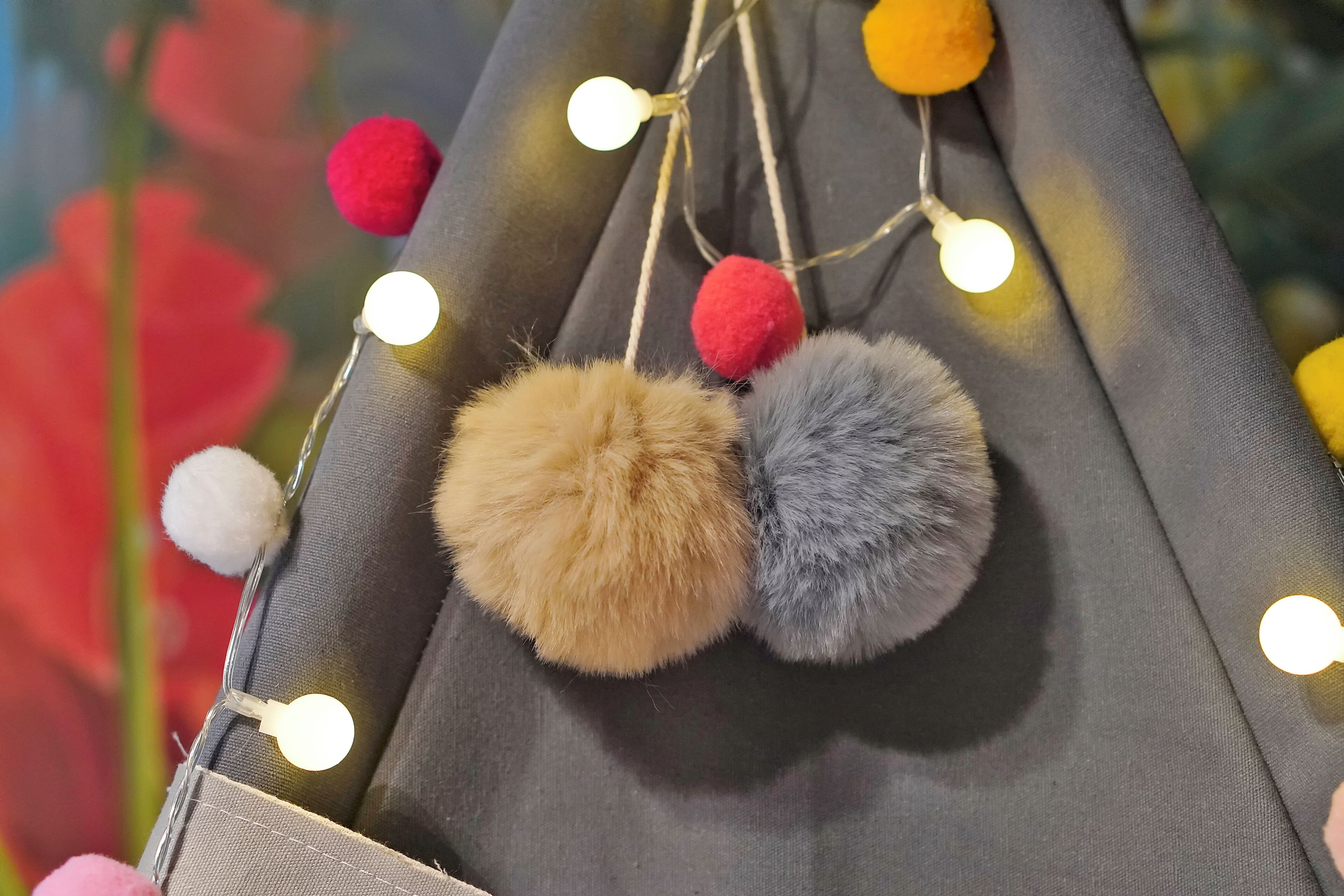 A close-up of a fabric with hanging lights and pom-poms.