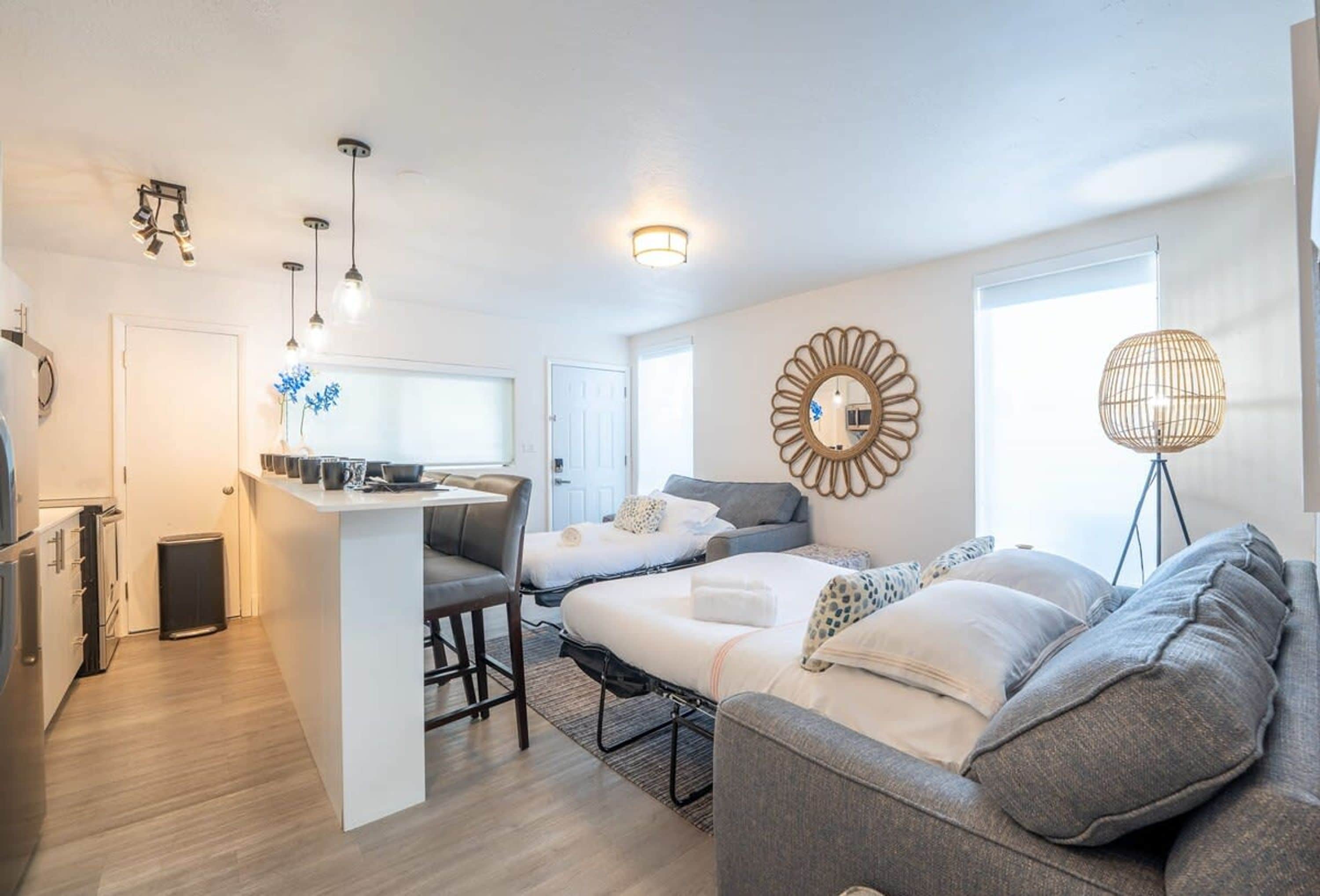 Un espacio habitable compacto con kitchenette, comedor y un dormitorio con cama grande y dos sofás.