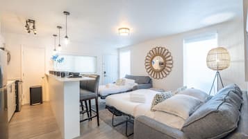 A compact living space with a kitchenette, a dining area, and a bedroom with a large bed and two sofas.