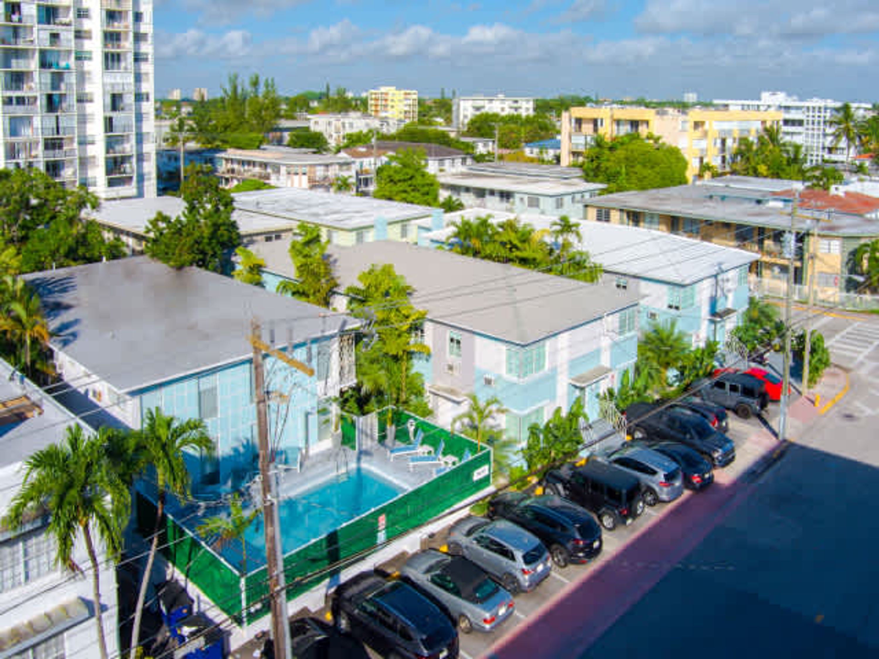 Un hôtel à plusieurs étages doté d’une piscine, d’un parking et de bâtiments adjacents.