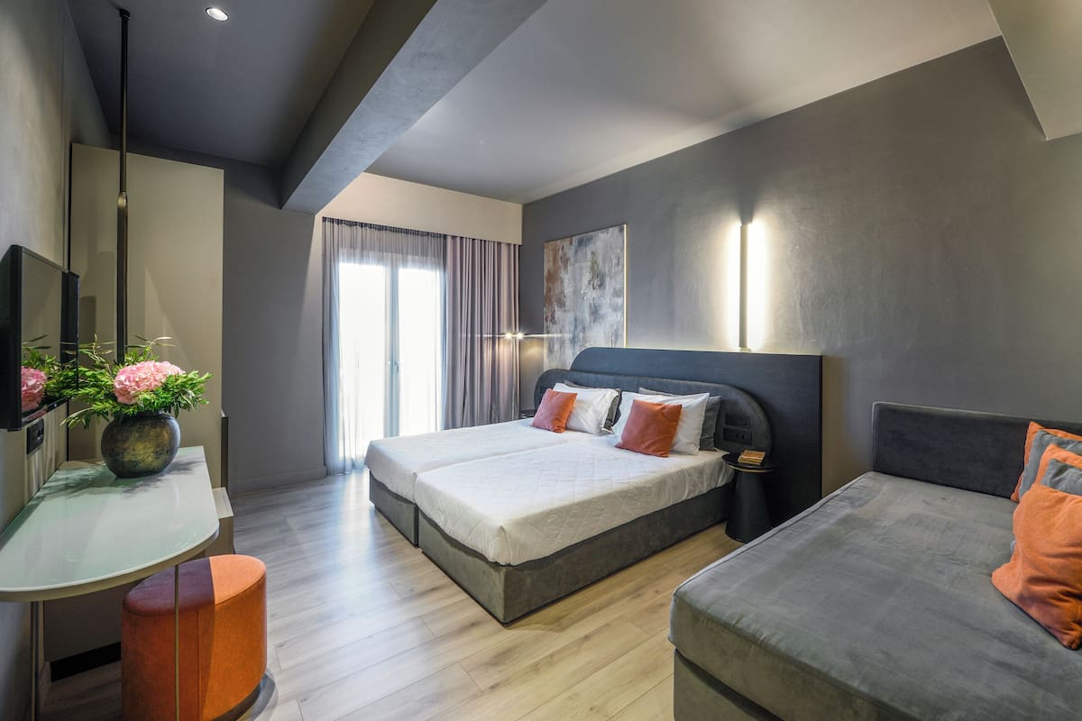 Una habitación de hotel moderna con una cama grande, un escritorio con un florero y un sofá.
