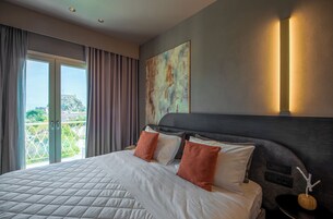 Habitación de hotel con una cama grande, vistas a un balcón y un cuadro en la pared.