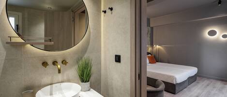 A modern bathroom with a round mirror, a white sink, and a potted plant.