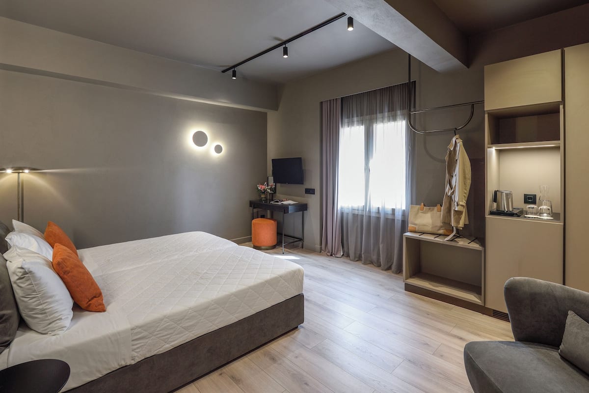 Una habitación de hotel moderna con una cama grande, un escritorio, un televisor y un armario.