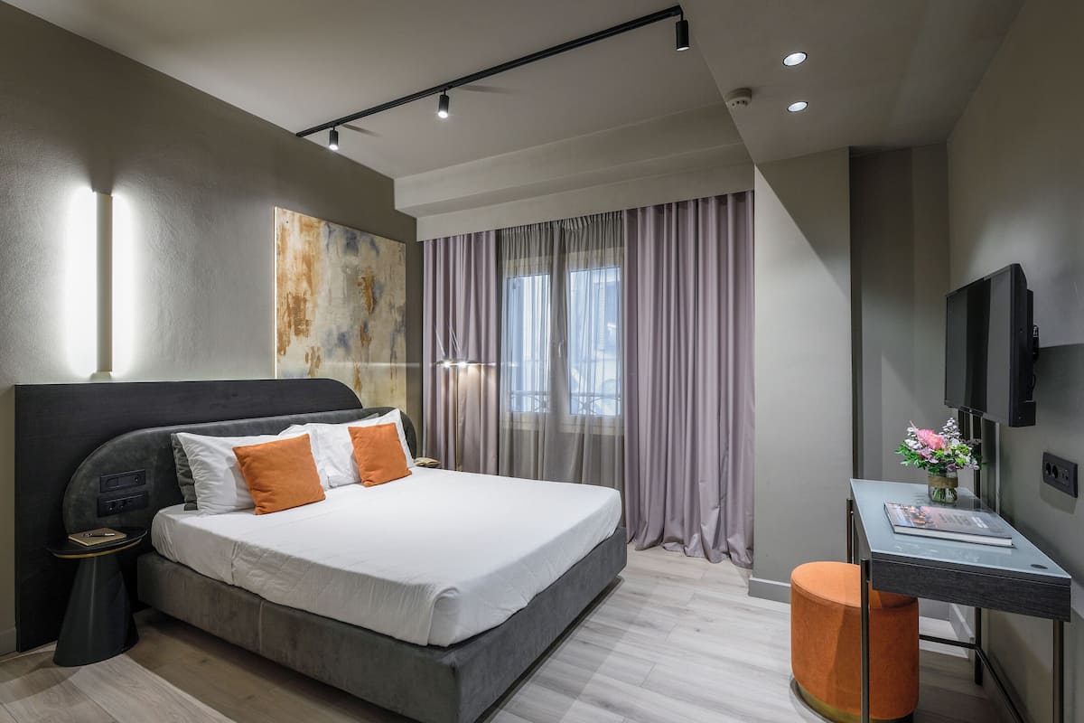 Un dormitorio moderno con una cama grande, un escritorio y un televisor.