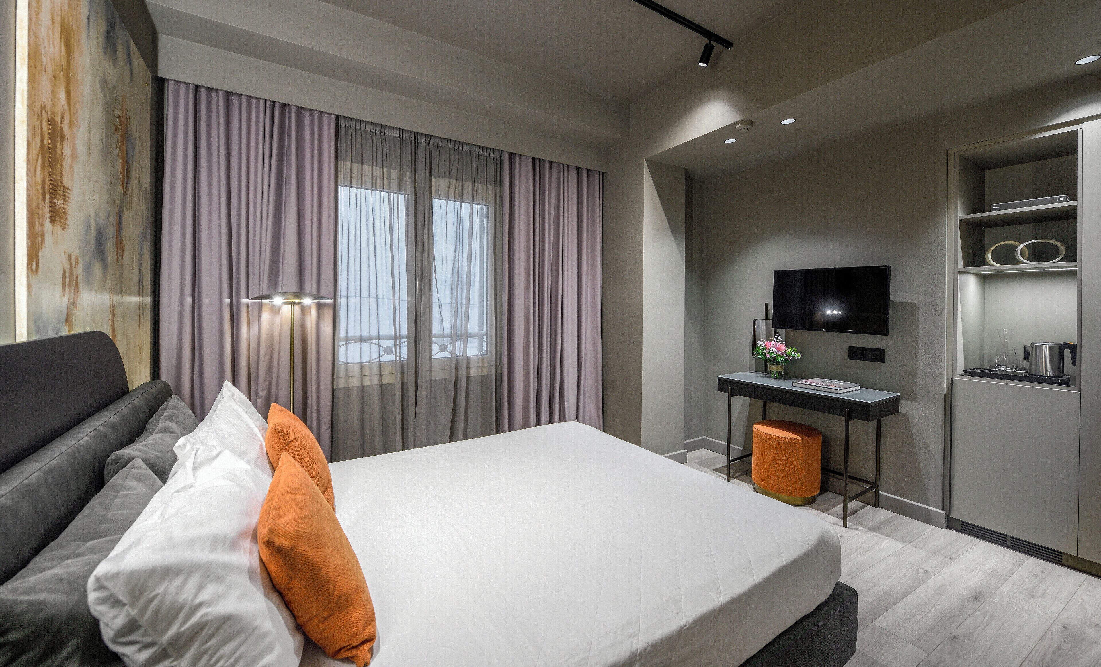 Una habitación de hotel moderna con una cama grande, un escritorio, un televisor y un minibar.