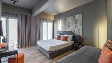 A modern bedroom with a large bed, a desk, and a sofa.