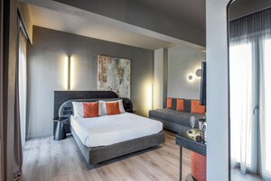 Una habitación de hotel moderna con una cama grande, un escritorio pequeño y un sofá.