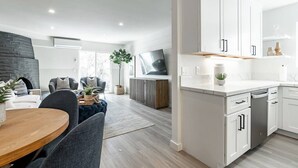 A modern kitchen with white cabinets, a built-in oven, and a dining area with a wooden table and chairs. - The Rosemont - La Jolla Luxury (La Jolla)