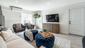A modern living room with a sofa, armchairs, a TV, and a wooden cabinet. - The Rosemont - La Jolla Luxury (La Jolla)