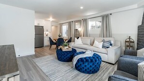 A modern living room with a sofa, ottomans, and a dining area with a table and chairs. - The Rosemont - La Jolla Luxury (La Jolla)