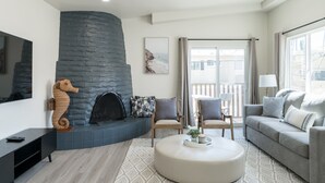 A modern living room with a stone fireplace, comfortable seating, and a large window offering a view.