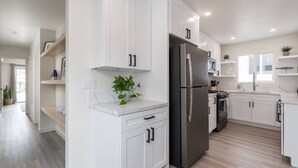 Una cocina moderna con armarios blancos, un refrigerador de acero inoxidable y piso de madera.