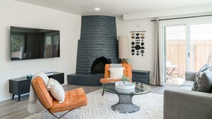 Una sala de estar moderna con chimenea de piedra, televisor de pantalla plana y asientos cómodos.
