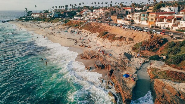 Un pueblo costero con playa, acantilados rocosos y edificios residenciales.
