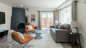 Una sala de estar moderna con chimenea, una mesa de centro de vidrio y un sofá gris.