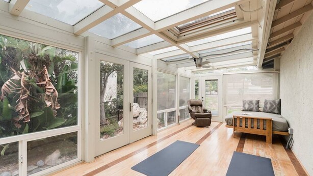 A spacious room with a large glass wall, a wooden floor, a bed, a chair, and two yoga mats. - Ocean View Retreat- 4 Blocks From Solana Beach (Solana Beach)