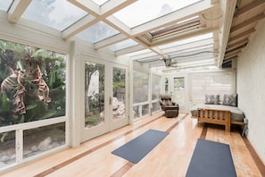 A spacious room with a large glass wall, a wooden floor, a bed, a chair, and two yoga mats. - Ocean View Retreat- 4 Blocks From Solana Beach (Solana Beach)