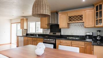 A modern kitchen with wooden cabinets, a black countertop, and a hanging light fixture.