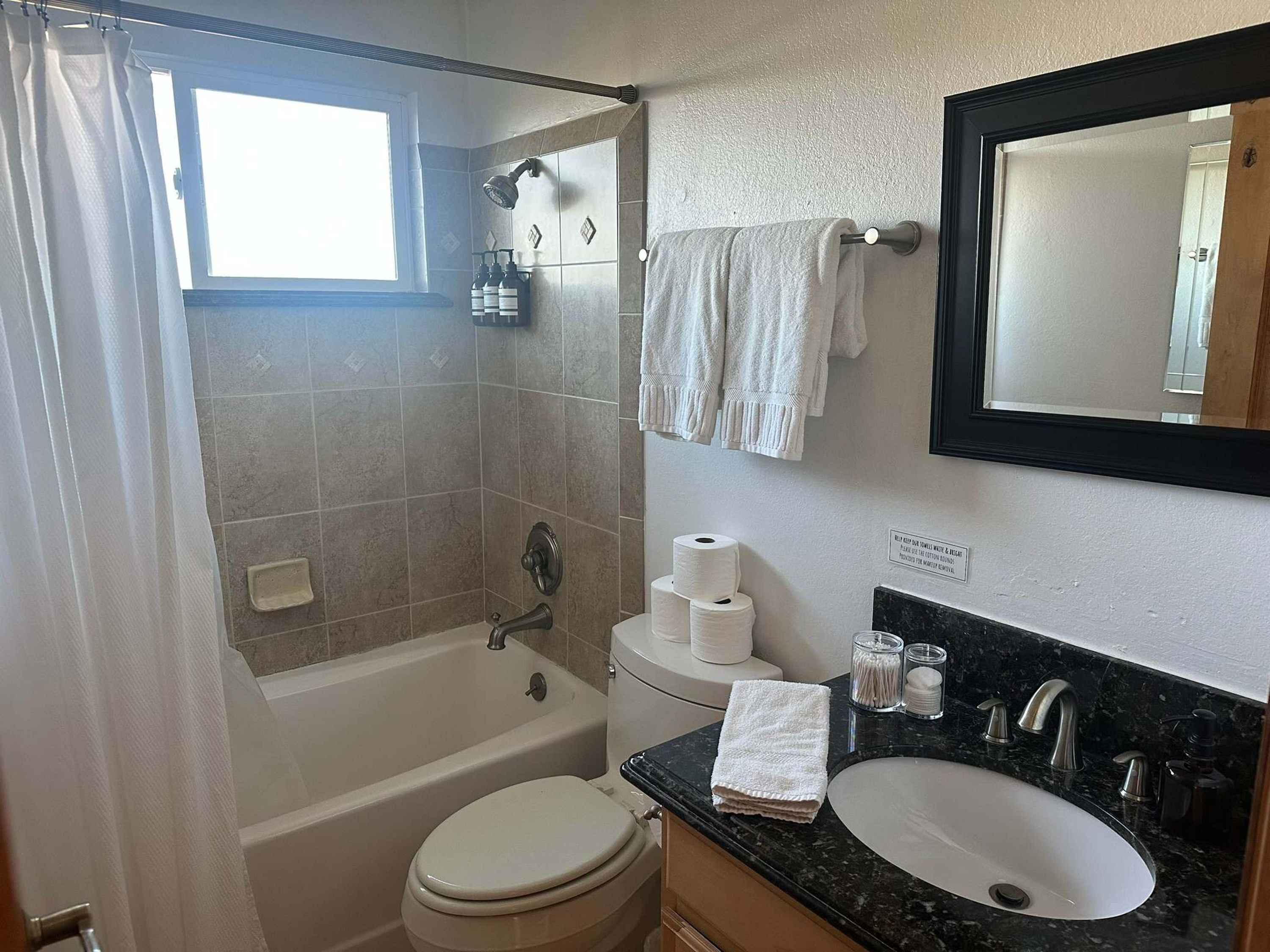A bathroom with a bathtub, toilet, sink, and a mirror.
