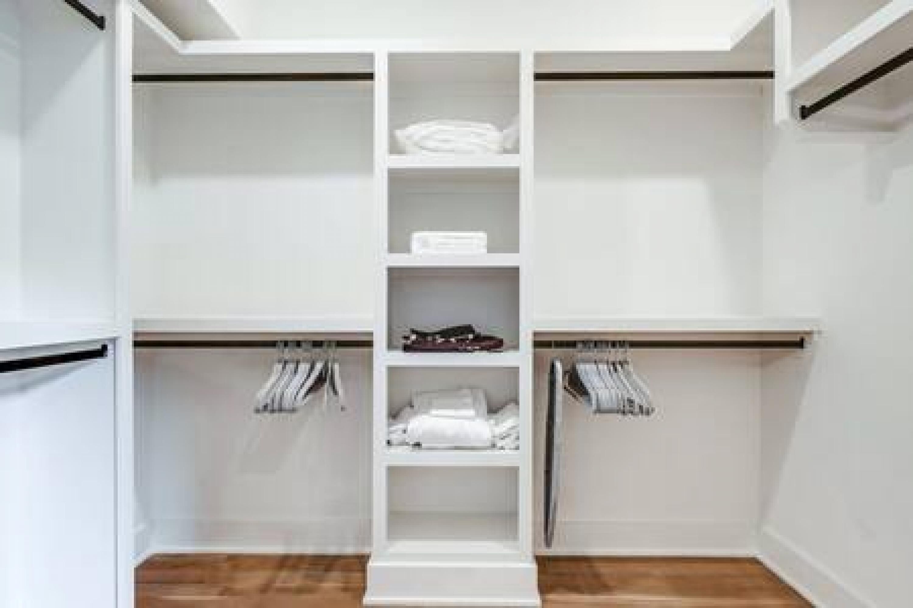 A white walk-in closet with multiple shelves and hanging space.