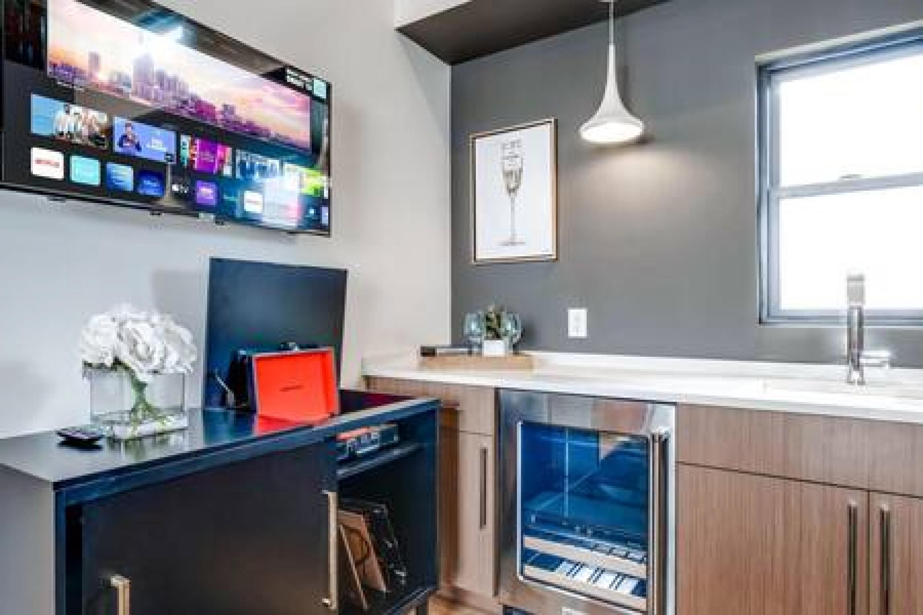 A modern kitchen with a built-in oven, a large window, and a flat-screen TV mounted above the counter.