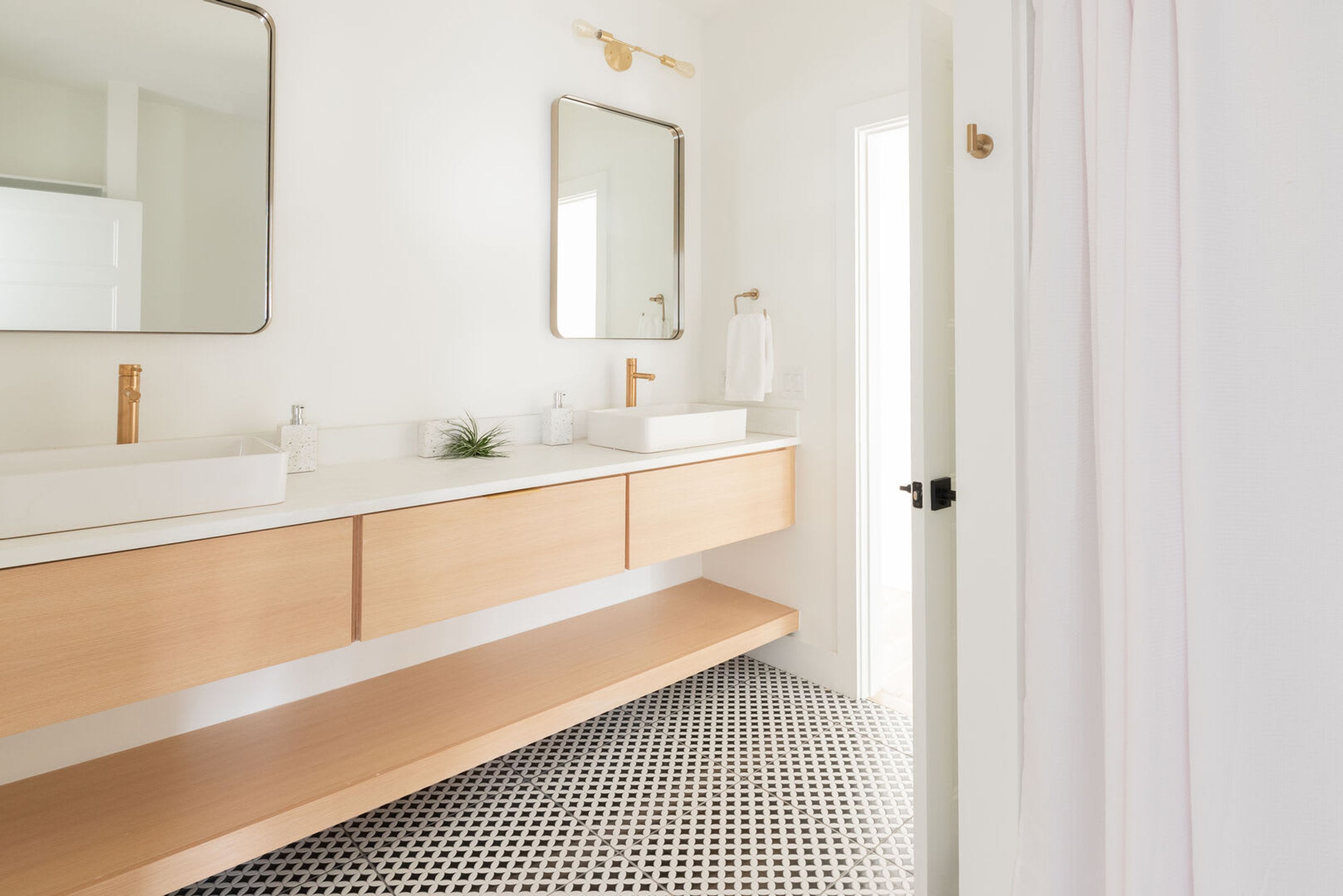A modern bathroom with a white vanity, a large mirror, and a patterned floor.