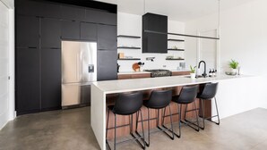 A modern kitchen with a large island, black bar stools, and stainless steel appliances. - Nash Chic Near DT Rooftop Luxe Comfort (Nashville)