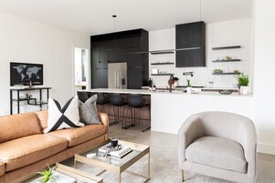A modern kitchen with black cabinets, a white countertop, and a bar area with stools.