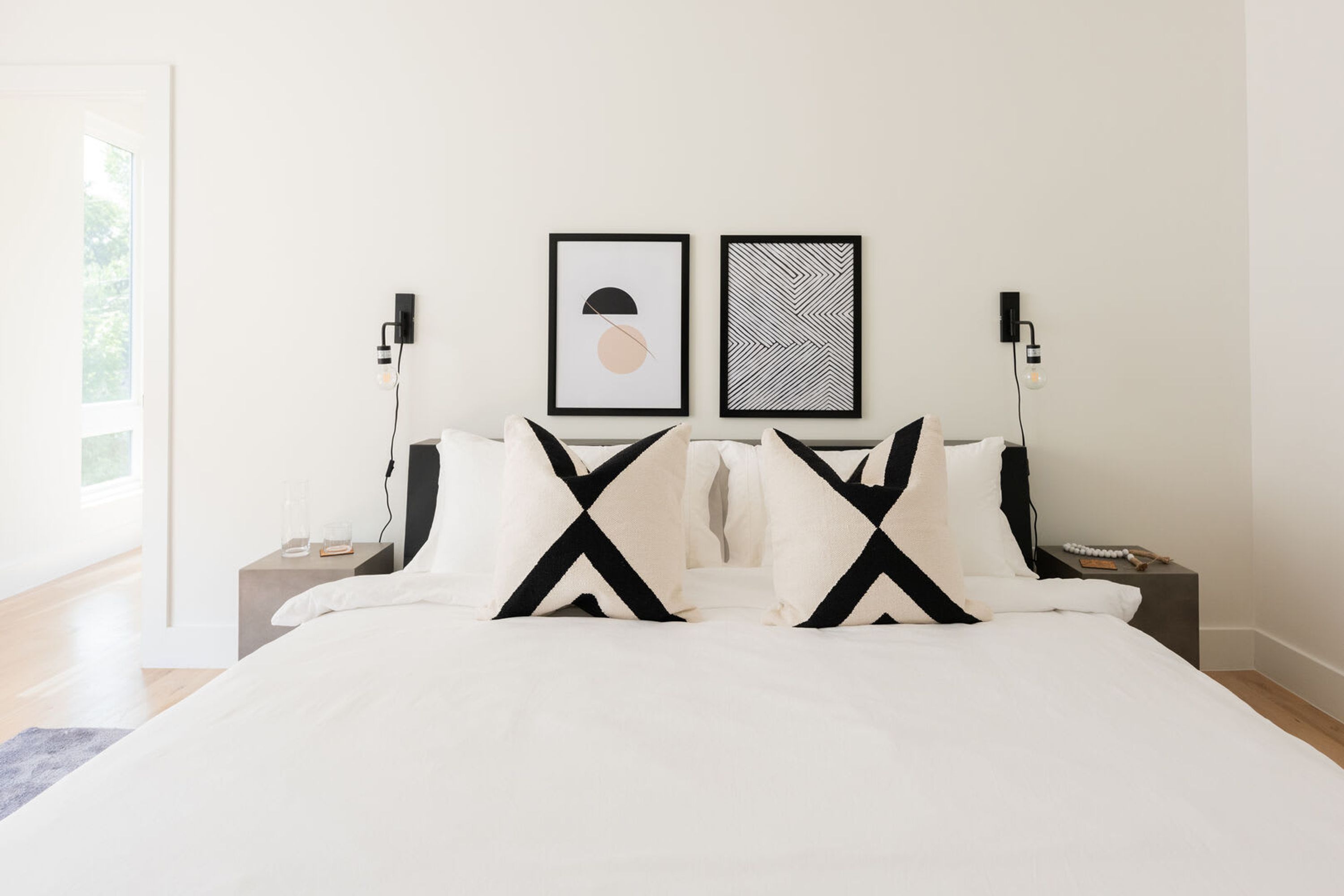 A modern bedroom with a large bed, two bedside tables, and two wall-mounted light fixtures.