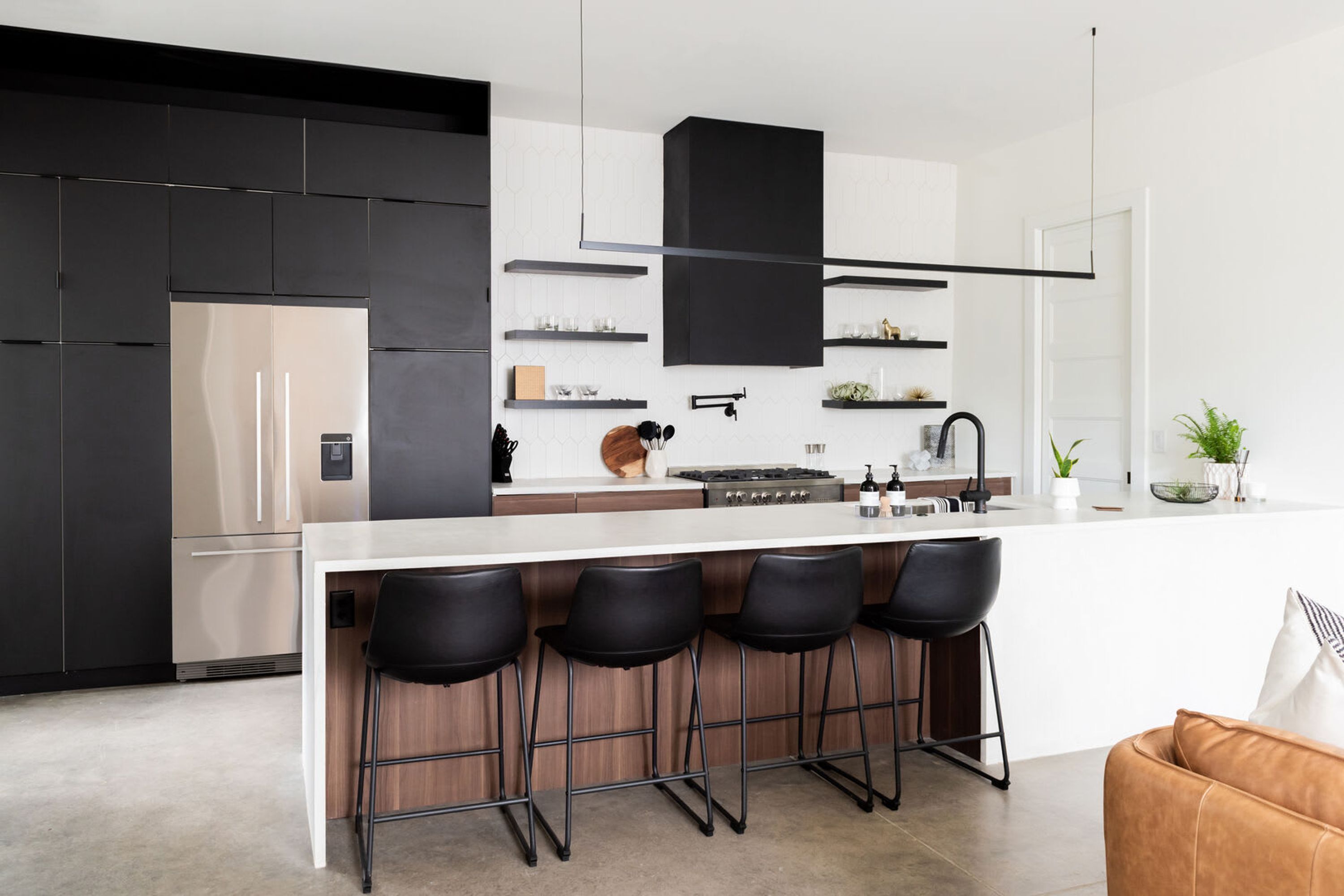 A modern kitchen with a central island, bar stools, and a built-in oven.
