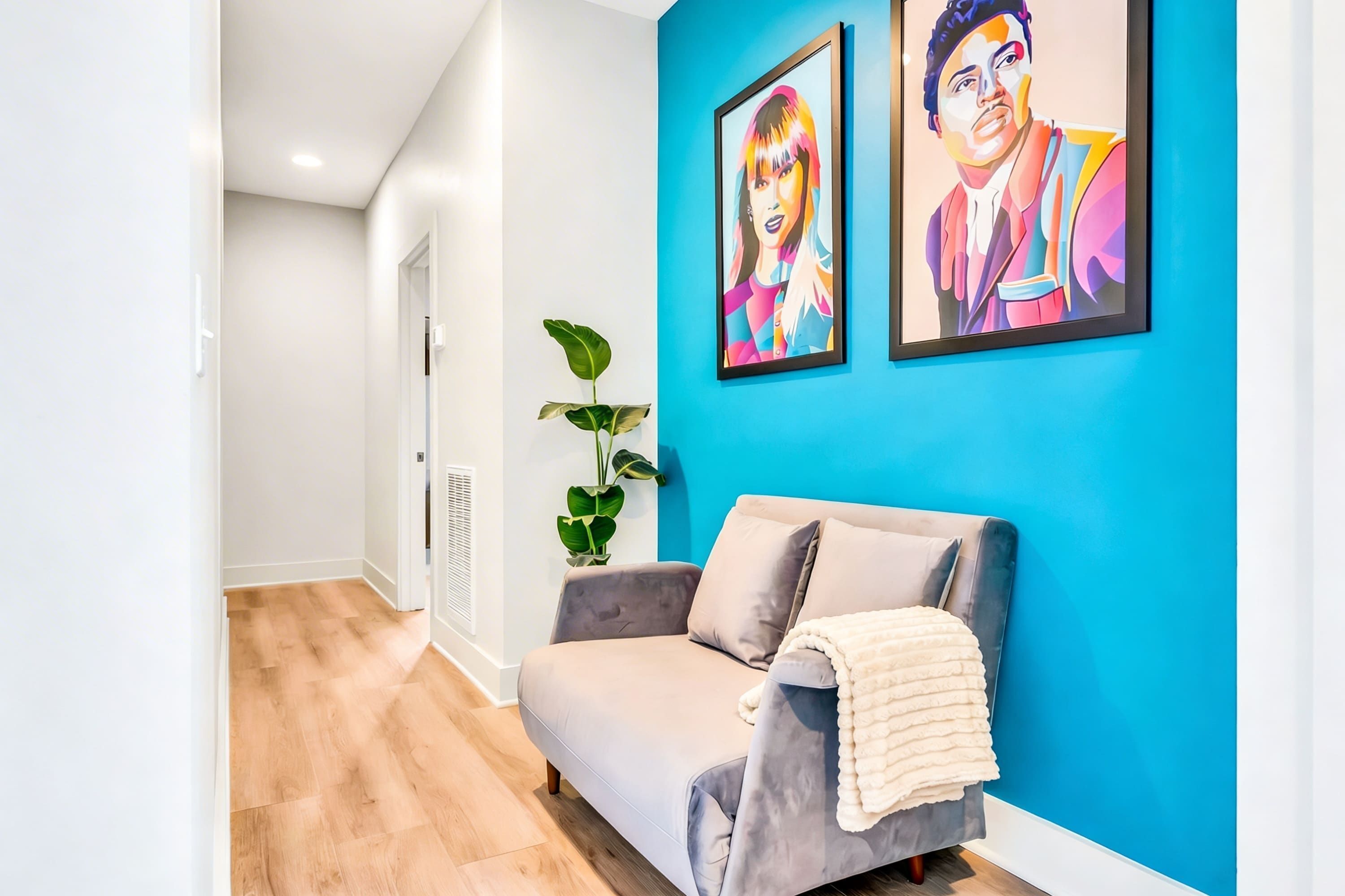 Un salon moderne avec un canapé gris, un mur d’accent bleu et deux œuvres d’art encadrées.