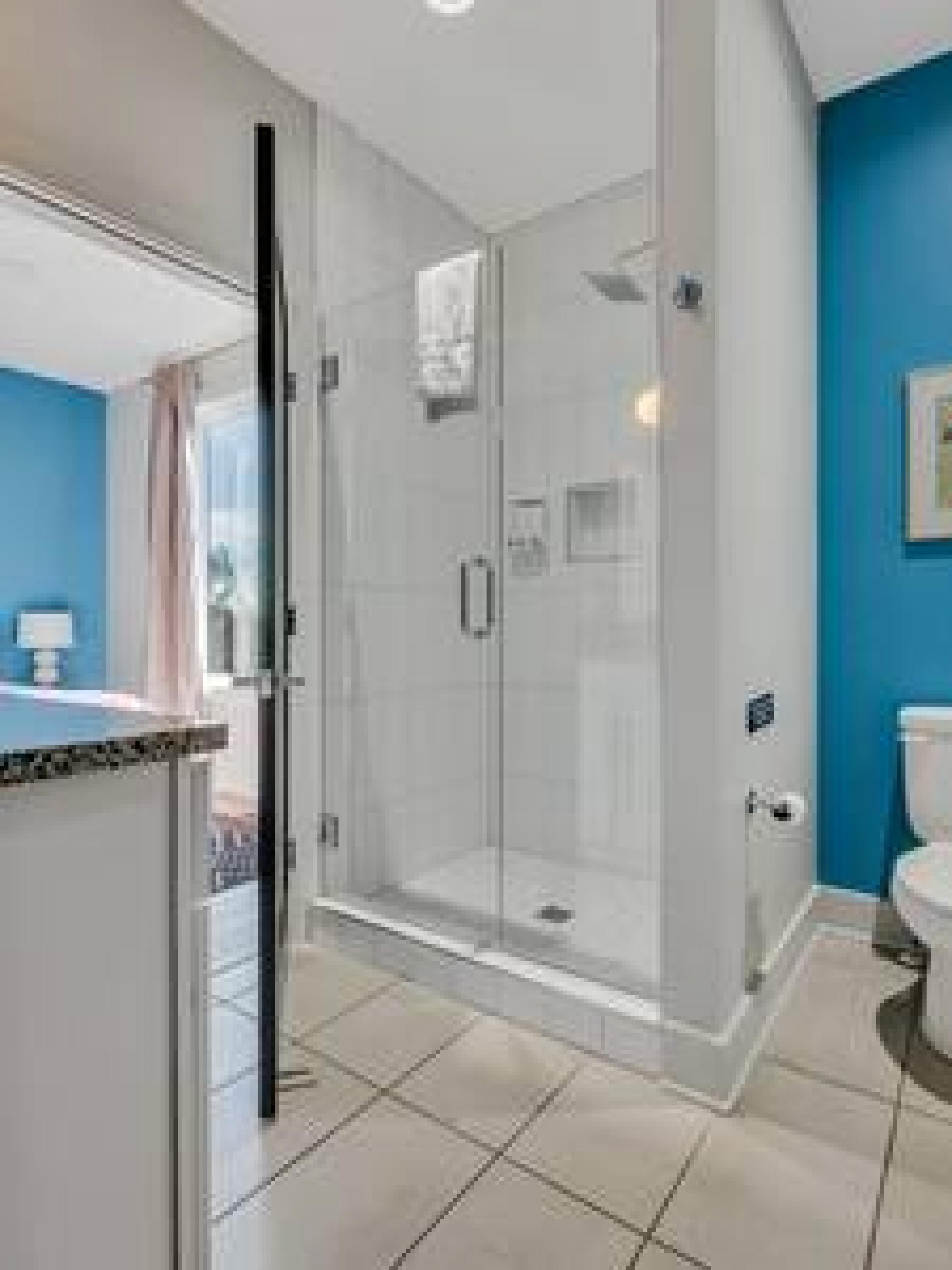 A modern bathroom with a glass shower enclosure, a toilet, and a sink with a countertop.