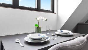 Una mesa de comedor con platos, cubiertos y un florero con flores.