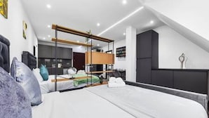 A modern hotel room with a bunk bed, a desk, and a kitchenette. - Modern Spacious Suite Sleeps 4 in Central London (London)