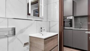 A modern bathroom with a wooden vanity, a mirror, and a built-in sink. - Luxury Spacious 2 Person Suite in North London (London)