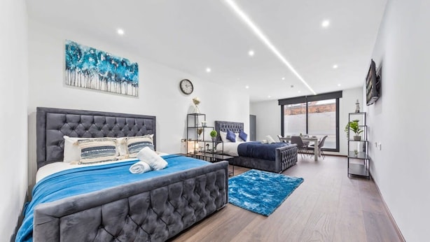 Une chambre moderne avec un grand lit, un petit canapé et un espace bureau.