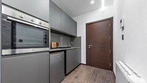 Une cuisine moderne dotée d’appareils électroménagers en acier inoxydable, de meubles de rangement gris et d’un plancher en bois.