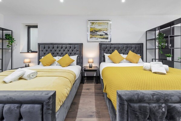 A hotel room with two beds, each with a tufted headboard, and a large painting above the beds. - Luxury Studio Suite Near Euston Central London (London)