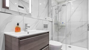 A modern bathroom with a marble vanity, a toilet, and a glass shower enclosure. - Serviced Studio Flat Near London Northern Line (London)