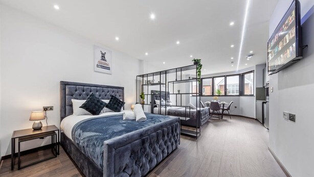A modern bedroom with a large bed, a desk, and a TV. - Serviced Studio Flat Near London Northern Line (London)