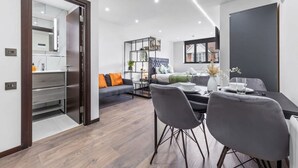 Ein modernes Wohnzimmer mit Essbereich, einer Couch, einem Couchtisch und einem Bücherregal.