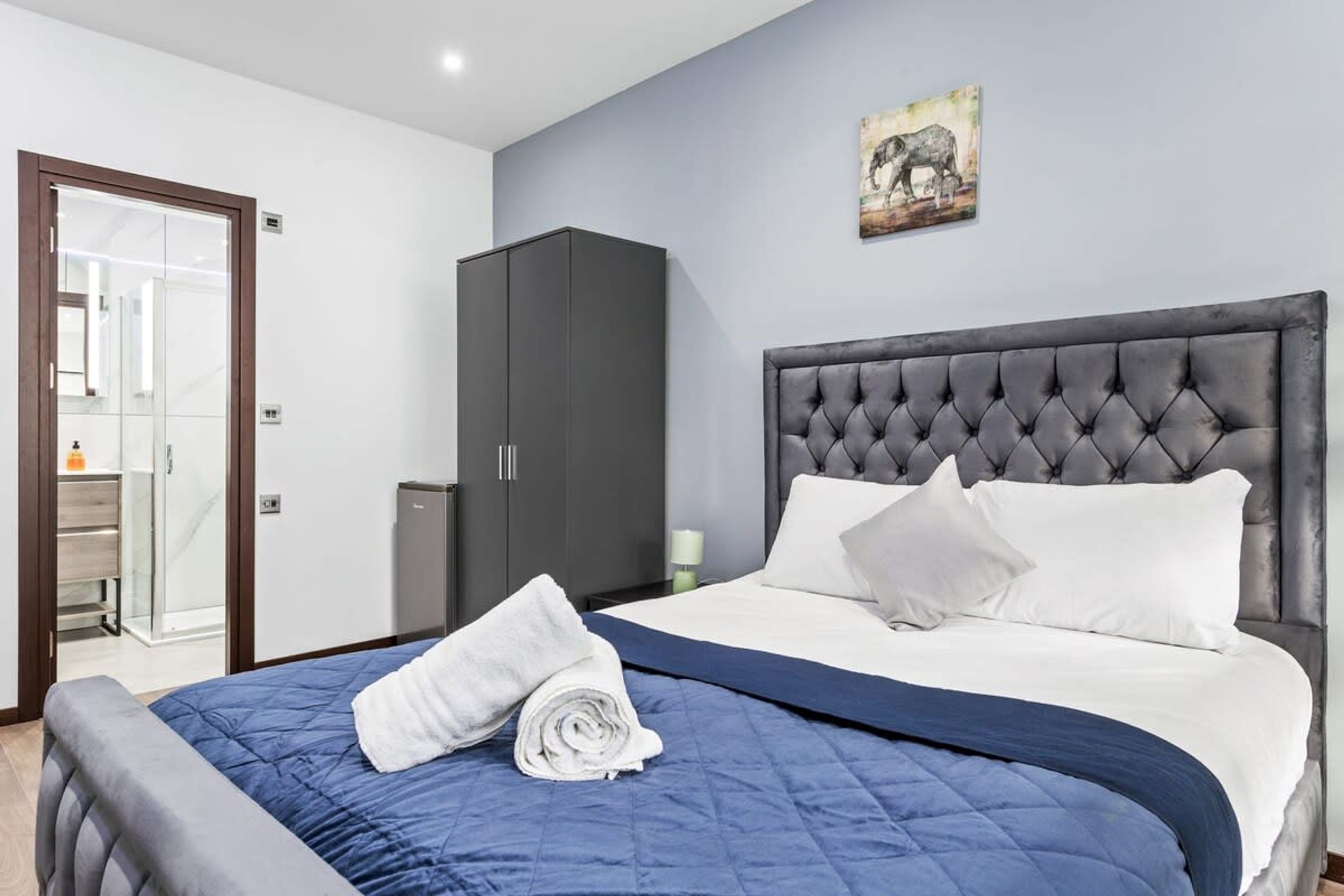 A bedroom with a large bed, a grey headboard, and a wardrobe.