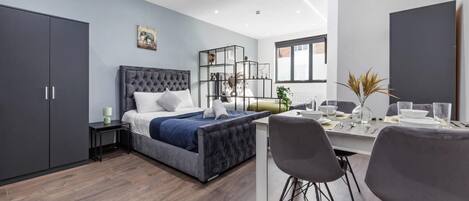 A modern bedroom with a bed, bedside table, and a desk with chairs.