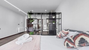A modern bedroom with a bed, a desk, and a seating area.