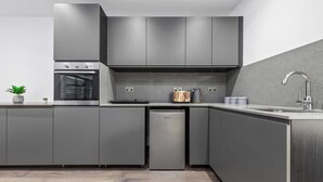 Een moderne keuken met grijze kastjes, een ingebouwde oven, een vaatwasser en een roestvrijstalen spoelbak.