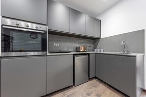 A modern kitchen with grey cabinetry, a built-in oven, a dishwasher, and a sink.