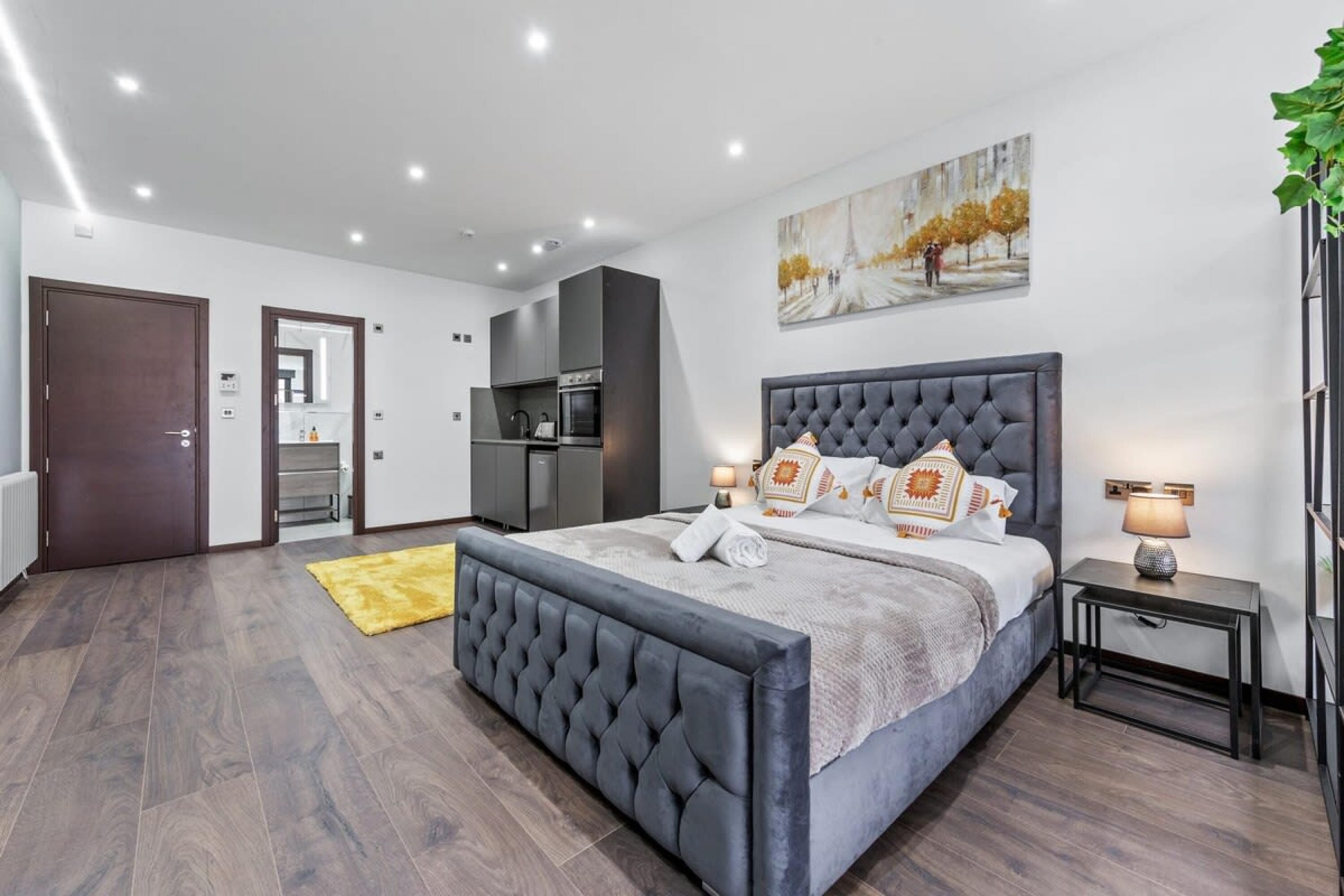 A modern bedroom with a large bed, a small bedside table, and a painting on the wall.