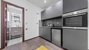 Una cocina moderna con gabinetes grises, horno empotrado y un refrigerador pequeño.