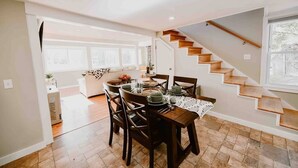 A dining area with a wooden table set for four, a staircase, and a view of the outdoors. - Little Landing Cottage-gorgeous View BBQ Wi-fi (Winthrop)